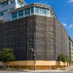 Construction site safety nets installed on scaffolding around a building under construction, designed to contain falling debris on large urban construction sites