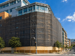Construction site safety nets installed on scaffolding around a building under construction, designed to contain falling debris on large urban construction sites