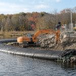 Temporary cofferdam installed at the edge of a body of water for water management on a construction site, used to contain and divert water during excavation work