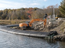 Batardeau temporaire installé en bordure d’un plan d’eau pour la gestion des eaux sur un chantier, utilisé pour contenir et dévier l’eau lors de travaux d’excavation