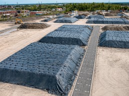 Toiles de recouvrement pour sols contaminés installées sur plusieurs monticules en chantier, utilisées pour contenir et protéger des matériaux excavés en environnement contrôlé