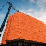 Industrial insulated tarp installed on a building under construction, used to protect the work site and maintain the temperature during work in cold weather.