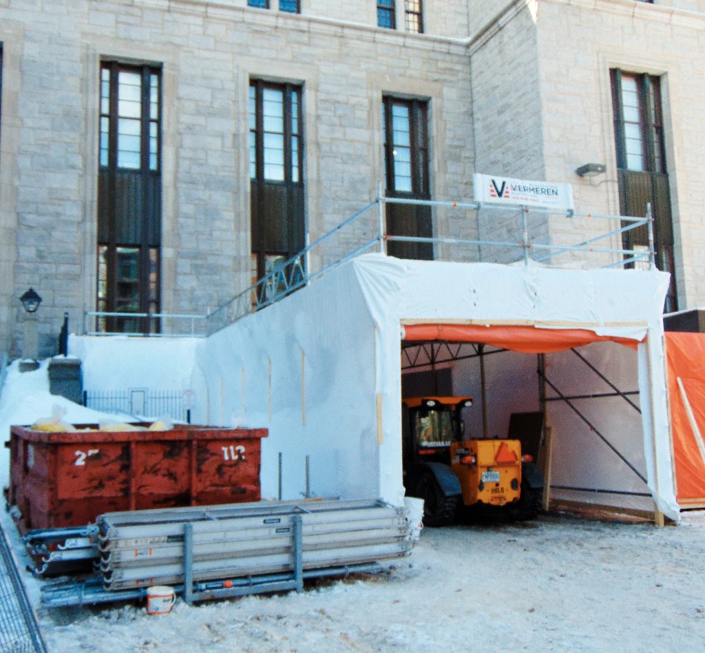 Film thermorétractable (shrink wrap) installé sur un échafaudage afin de créer un espace de confinement étanche pour des travaux de construction.
