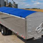 Blue grain tarp mounted on an aluminum grain trailer for the safe transport of grain and bulk products.